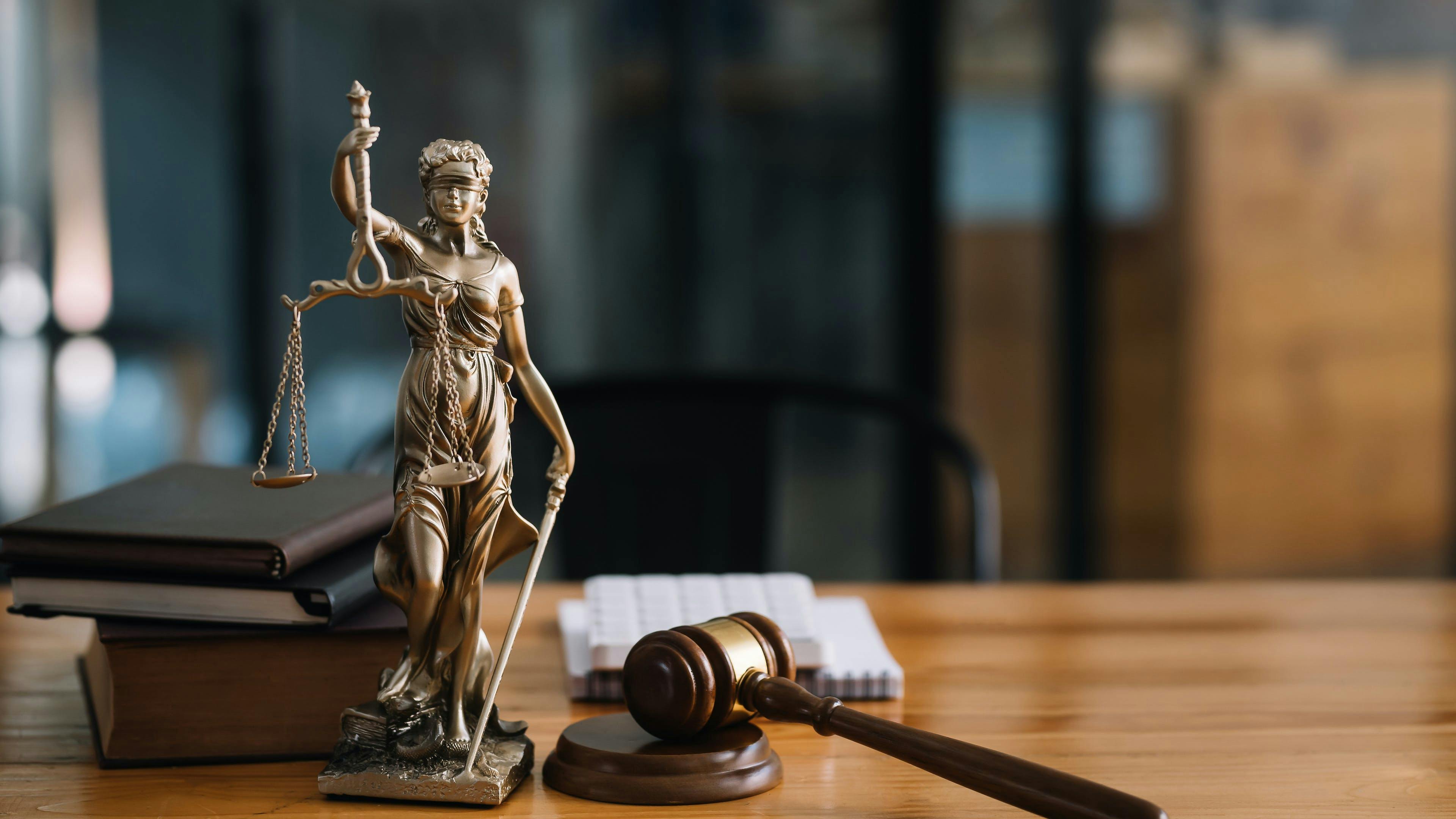 Statue of lady justice holding scales next to a gavel