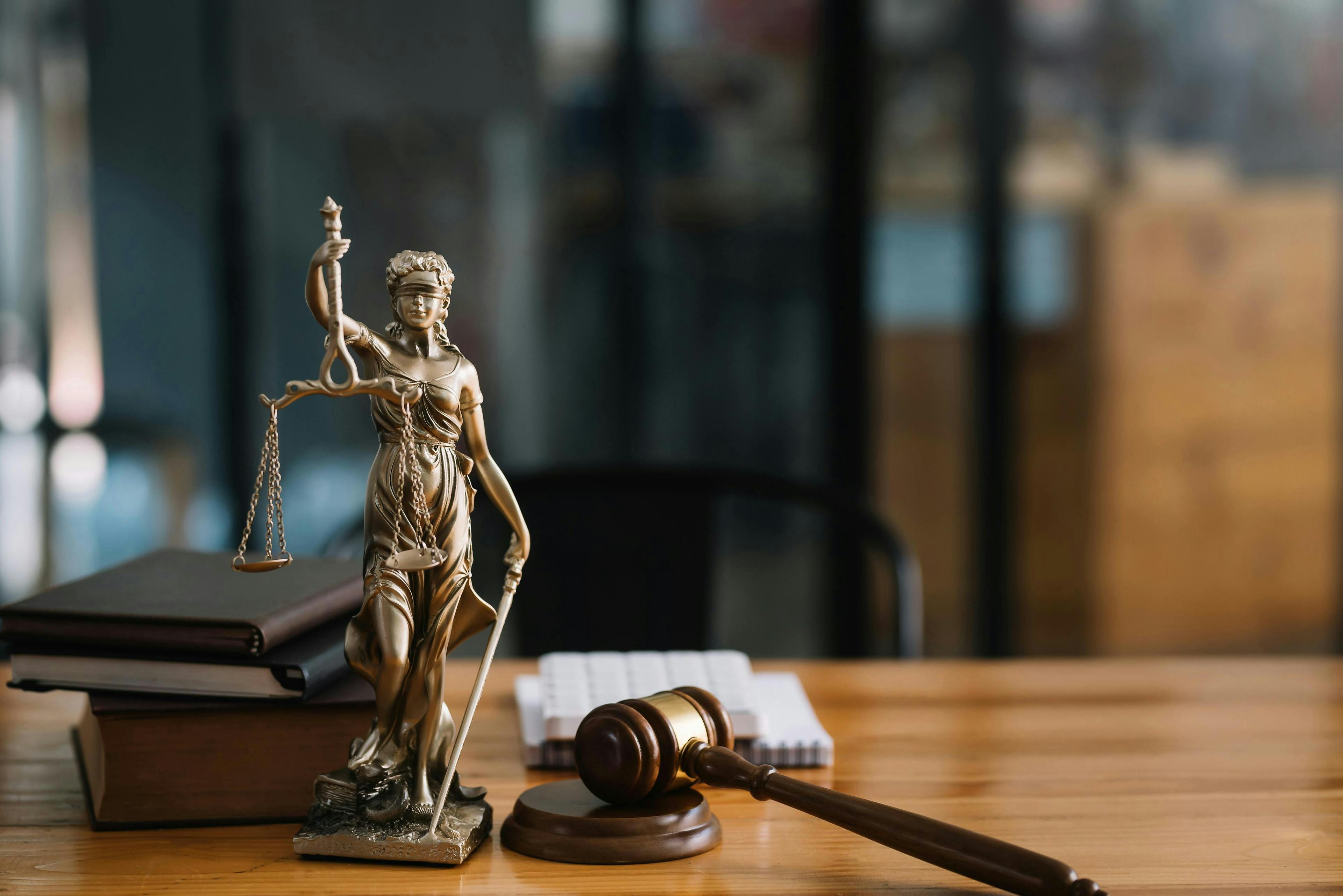 Statue of lady justice holding scales next to a gavel